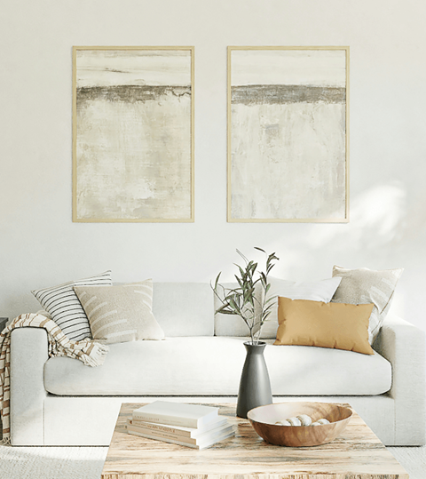 A living room with a white couch and two framed artworks on the wall.